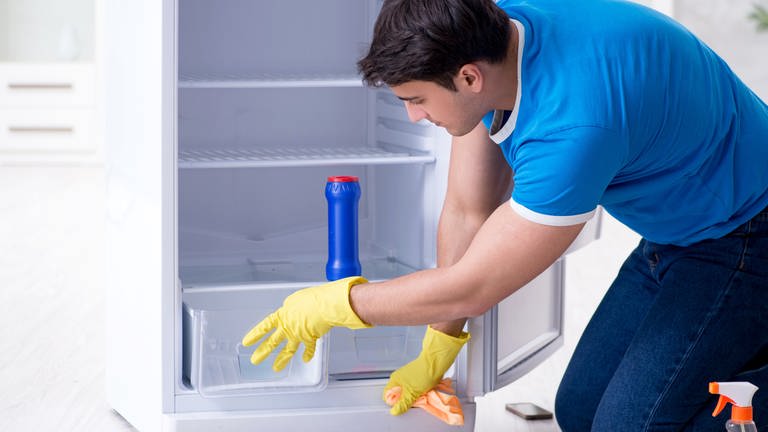Umweltfreundlich putzen: Mann reinigt Kühlschrank (Foto: Colourbox)