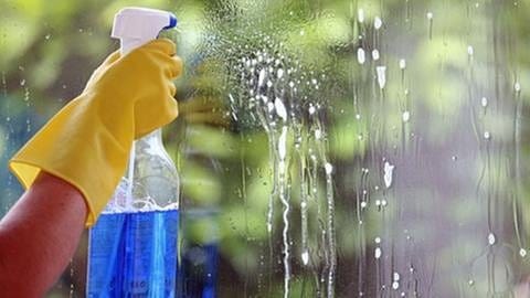 Jemand sprüht Reiniger an eine Fensterscheibe (Foto: © Colourbox.com -)