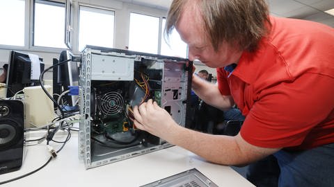 Mann arbeitet an einem reparaturbedürftigen Computer. (Foto: dpa Bildfunk, picture alliance/dpa/dpa-Zentralbild)