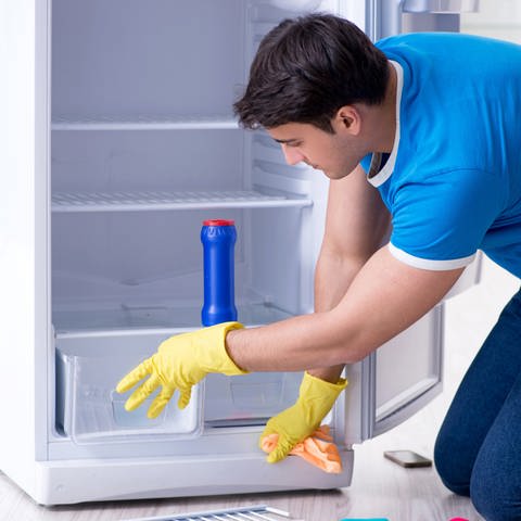 Umweltfreundlich putzen: Mann reinigt Kühlschrank