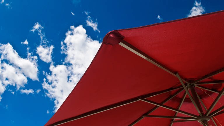 Roter Sonnenschirm vor blauem Himmel - reinigen, um den Sommer zu genießen