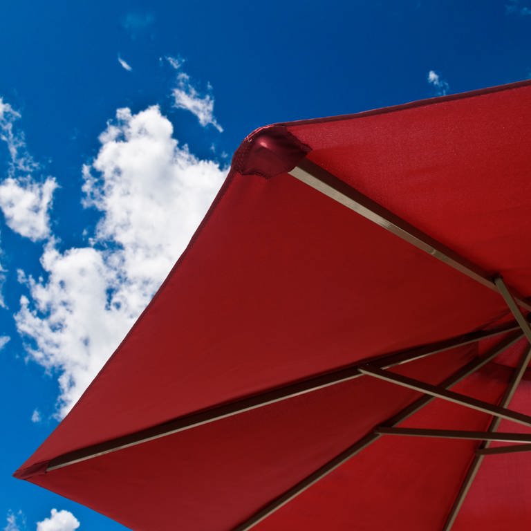 Roter Sonnenschirm vor blauem Himmel - reinigen, um den Sommer zu genießen