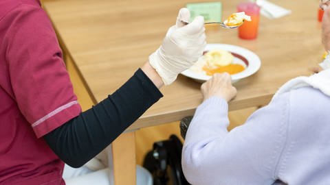 Pflege: Frau füttert Heimbewohnerin. Die Einstufung in den richtigen Pflegegrad ist wichtig. (Foto: IMAGO, IMAGO/Fotostand / Gelhot)