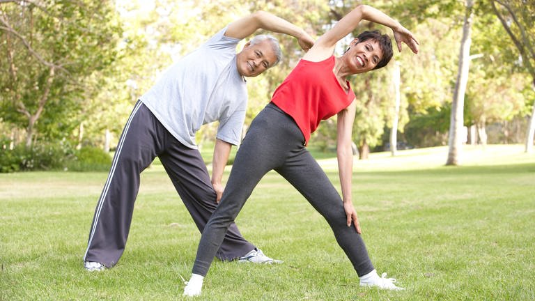 Gleichgewichtsübungen für mehr Fitness. Mann und Frau bewegen sich im Park