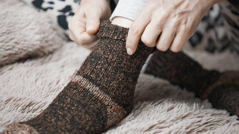 Frau zieht Socken an (Foto: IMAGO, IMAGO / YAY Images)