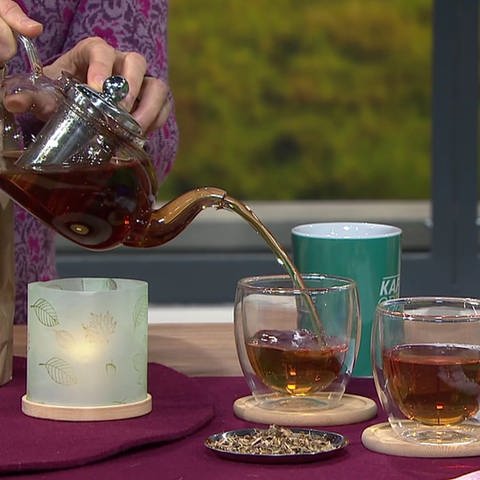 Frau gießt Tee in ein Glas