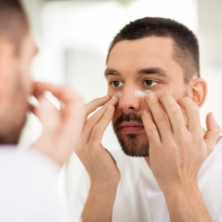 Mann cremt Gesicht ein - Hautpflege im Winter