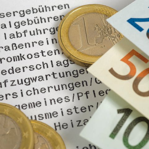 Geldscheine und Euro-Stück auf Liste mit Nebenkostenabrechnung