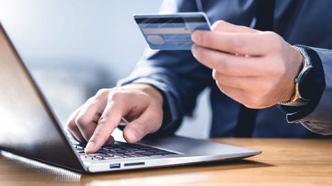 Mann mit Kreditkarte ins Laptop, um im Internet einzukaufen (Foto: Colourbox)
