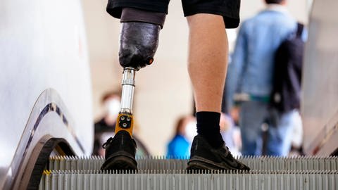 Ein Mann mit Behinderung fährt auf einer Rolltreppe - Schwerbehindertenausweis