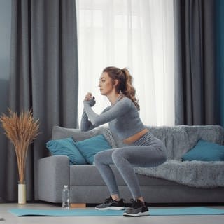 Frau macht Kniebeugen - 5-Minuten-Fitness: So schonen Sie Ihren unteren Rücken