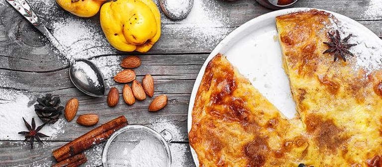 Ein hausgemachter Kuchen auf einem Tisch mit Puderzucker, Mandeln, Äpfeln. (Foto: Getty Images, Thinkstock -)