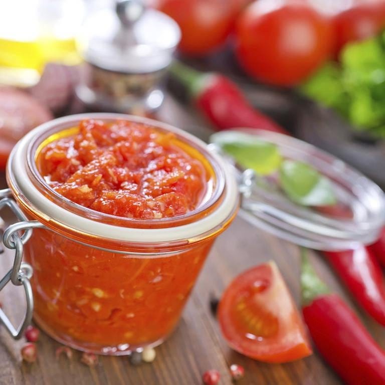 Tomatensauce im Glas, dekoriert mit Tomatenstücken und Chilischoten (Foto: Getty Images, Thinkstock -)