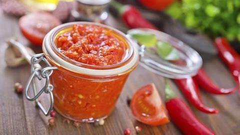Tomatensauce im Glas, dekoriert mit Tomatenstücken und Chilischoten (Foto: Getty Images, Thinkstock -)