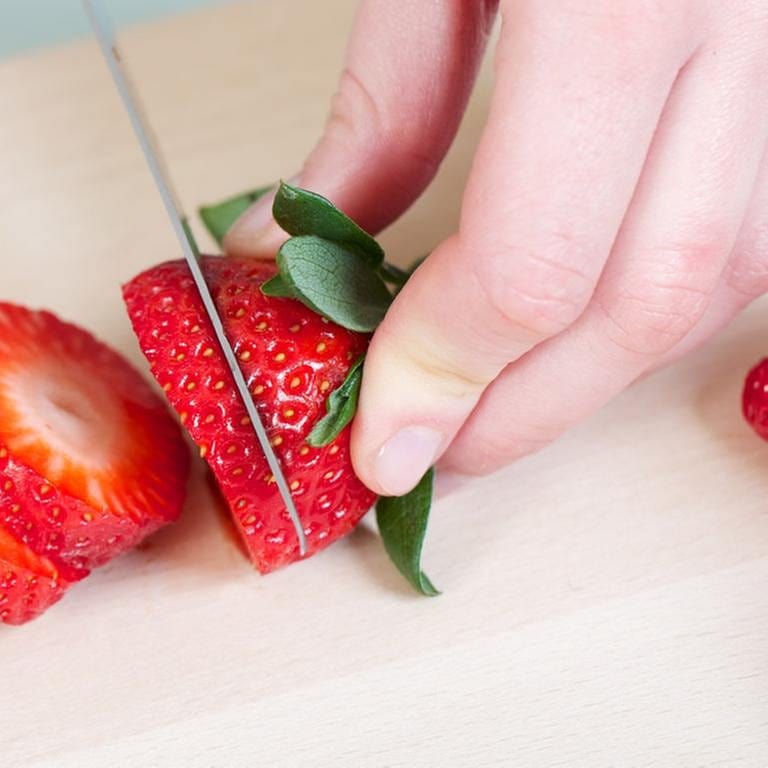 Eine Frau schneidet Erdbeeren auf. (Foto: Getty Images, Thinkstock -)