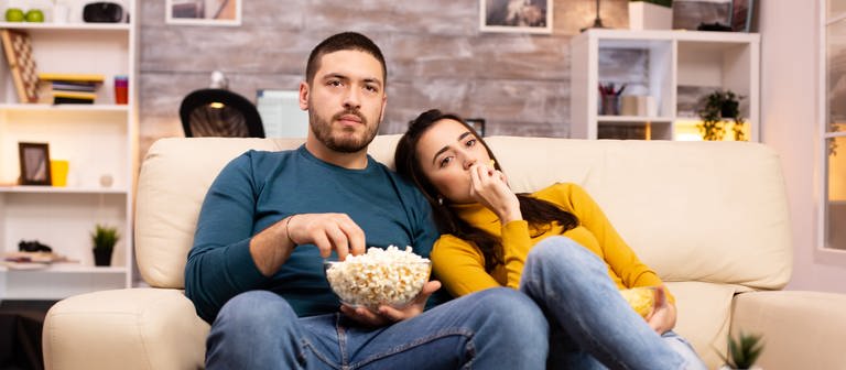 Paar sitzt vor dem Fernseher und isst Popcorn (Foto: Colourbox)