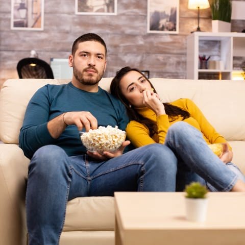 Paar sitzt vor dem Fernseher und isst Popcorn (Foto: Colourbox)