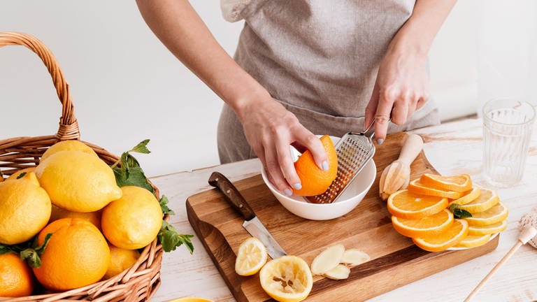 Frau drückt Grapefruit und Orangen aus