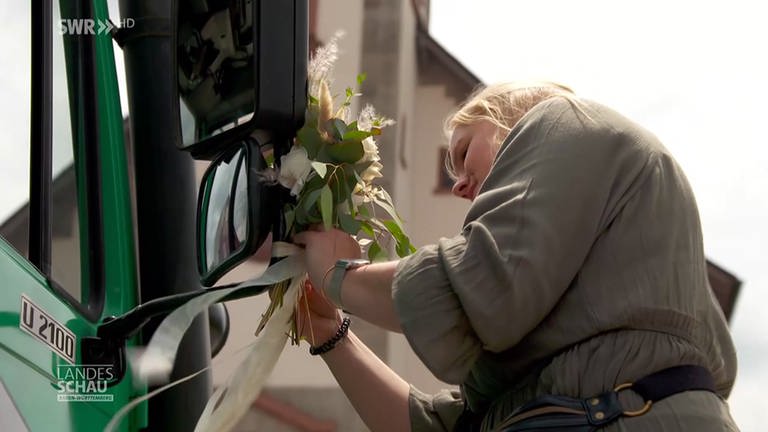 Frau bindet Hochzeitsblumen ans Fahrzeug (Foto: SWR)