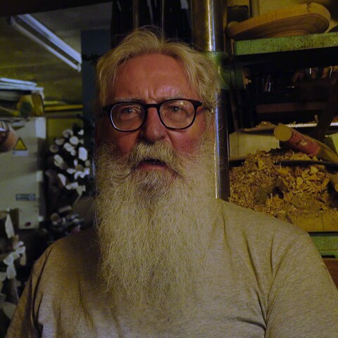 Ein älterer Mann mit langem Rauschebart steht in seiner Werkstatt voller Holz (Foto: SWR)