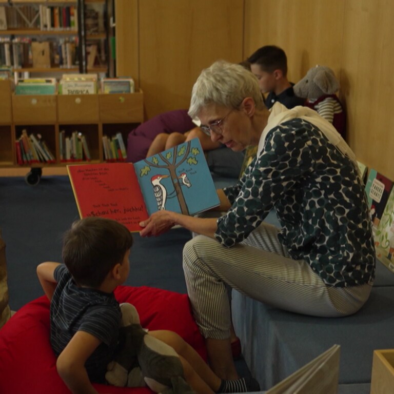 Eine ältere Frau zeigt einem kleinen Jungen ein Buch.  (Foto: SWR)