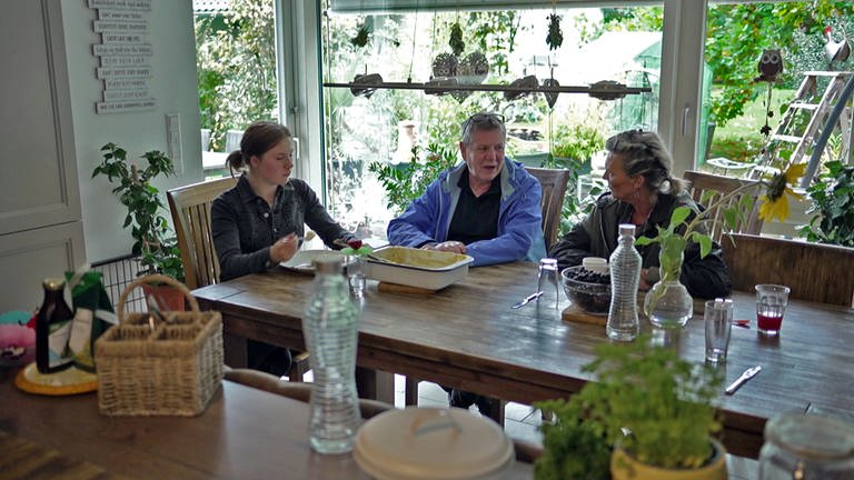 Kinderdorf Oberberken - Mädchen, Vater und Pflegemutter sitzen am Tisch in der Küche (Foto: SWR)