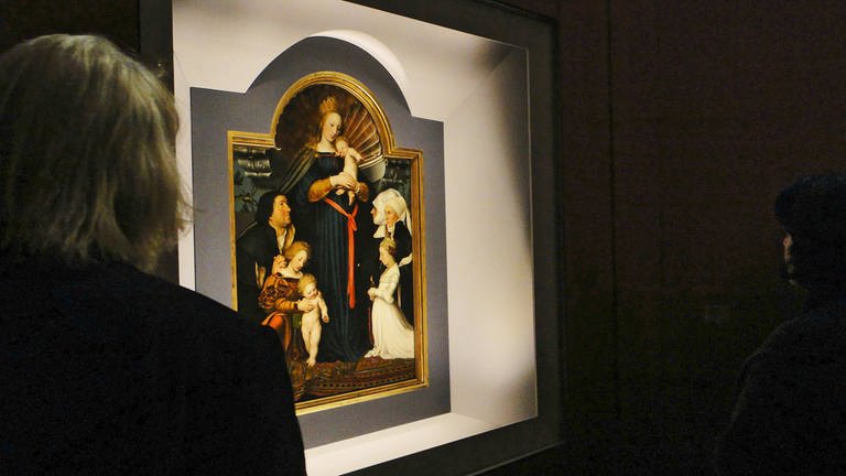 Leute betrachten eine Wandtafel, auf der eine Madonna abgebildet ist (Foto: IMAGO, imago stock&people -)