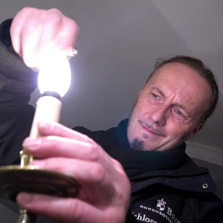 Mann tauscht Glühbirne aus (Foto: SWR)