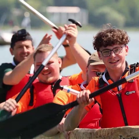 Junge Teilnehmer einer Einbaum-Regatta auf ihrem Boot im Wasser