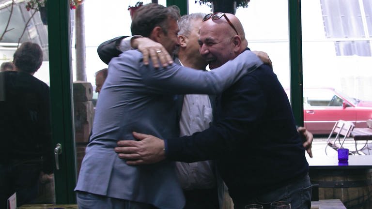Drei Männer umarmen sich