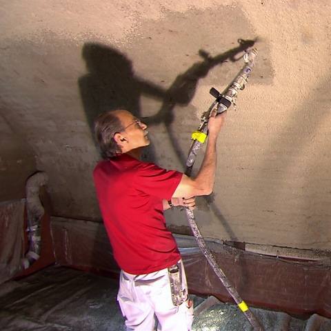 Ein Handwerker arbeitet mit einem Gerät in einem Gewölbekeller