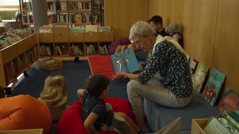 Eine ältere Frau zeigt einem kleinen Jungen ein Buch.  (Foto: SWR)