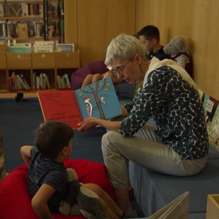 Eine ältere Frau zeigt einem kleinen Jungen ein Buch. 