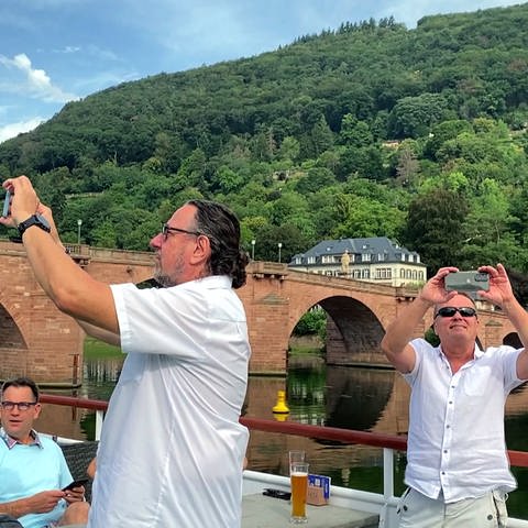Bootsfahrt auf dem Neckar in Heidelberg: Touristen fotografieren Sehenswürdigkeiten