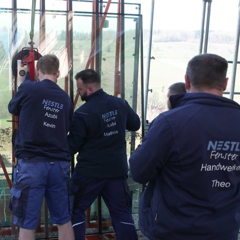 Männer hängen ein großes Fenster an den Kran