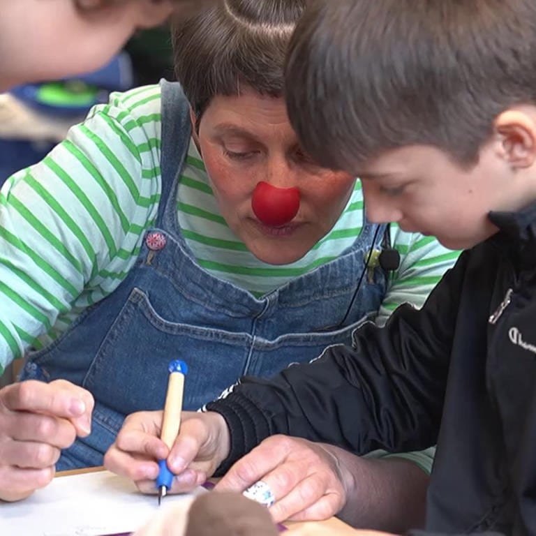 Als Clown verkleidete Frau hilft Kindern mit Schulaufgaben (Foto: SWR)