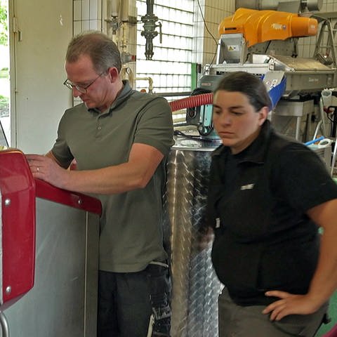 Zwei Mitarbeiter stehen an einer Weinpresse im Weingut Graf Adelmann in Kleinbottwar