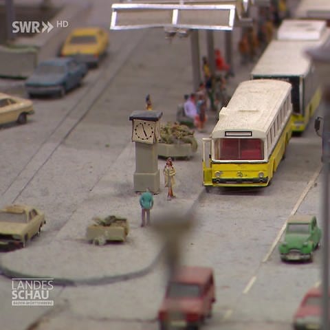 Miniaturstraße mit Autos, Bussen und Menschen