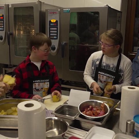 Zwei Kinder mit Down-Syndrom bereiten in der Küche ein Gericht vor