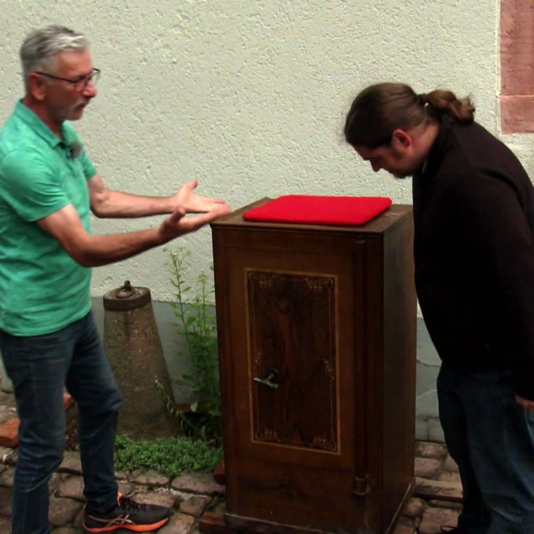Zwei Männer stehen neben einem Tresor, der vom Heimatmuseum in Epfenbach versteigert wird