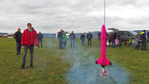 Ein pinkes Raketenmodell wird auf einer Wiese gezündet (Foto: SWR)