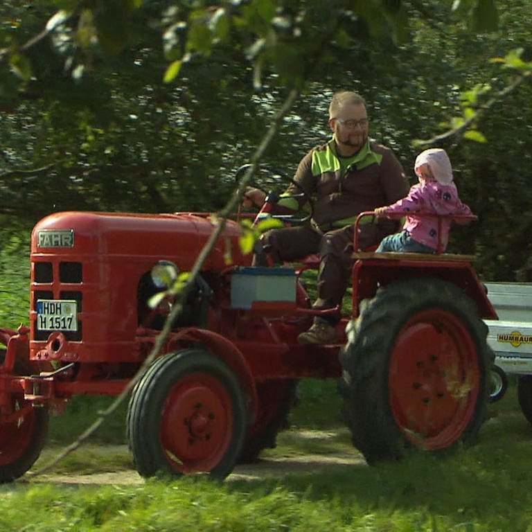 Man fährt mit Kindern auf dem Traktor durch Streuobstwiesen