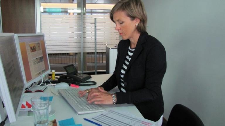 Moderatorin Annette Krause vor Computer, schaut konzentriert und tippt auf Tastatur
