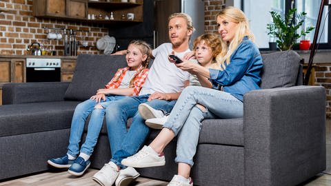 Familie sitzt auf der Couch vorm Fernseher. (Foto: Colourbox)