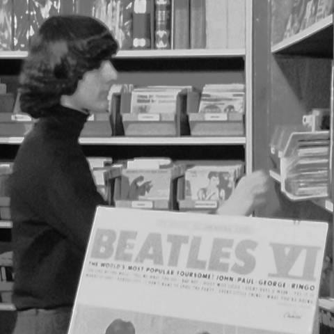 Der 15-jährige Thomas zieht eine Schallplatte der Beatles aus dem Regal, er trägt auch eine Frisur nach ihrem Vorbild. (Foto: SWR)