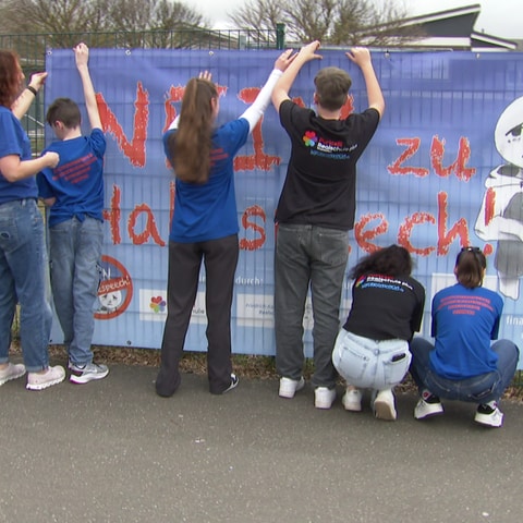 Jugendliche hängen ein Banner mit der Aufschrift "Nein zu Hatespeech" an einen Zaun (Foto: SWR)