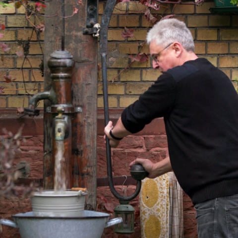 Alfred Schmitt pumpt Wasser im Freien
