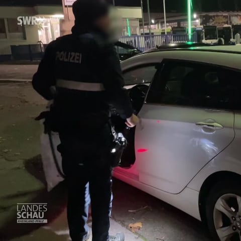 Polizist steht bei geöffnetem Auto