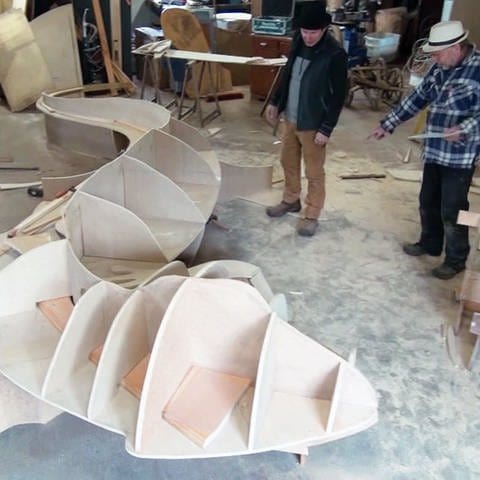 Zwei Männer bauen eine Holz-Echse (Foto: SWR)