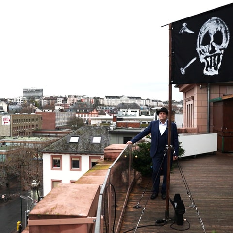 Niels Sonnemann neben der Piratenflagge auf dem Dach des Mainzer Staatstheaters. (Foto: SWR)